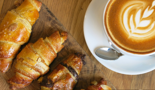 chocolate croissant and designed foam cup of coffee