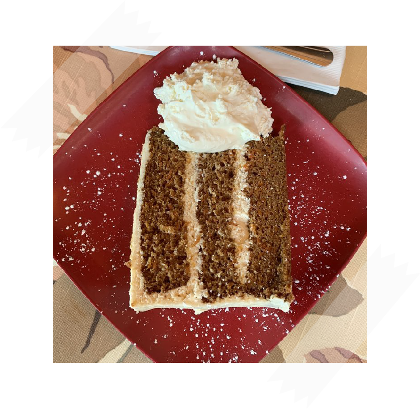 carrot cake with powdered sugar and whipped cream